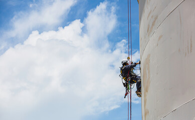 Male worker down height tank roof rope access safety inspection thickness weld of storage tank. © chitsanupong