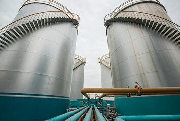 Tank farm in industry Thailand with white oil and petrol silos under blue