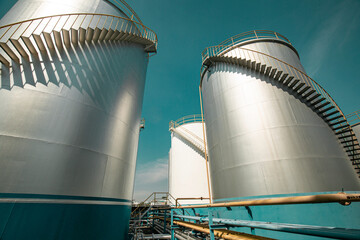 Tank farm in industry Thailand with white oil and petrol silos under blue