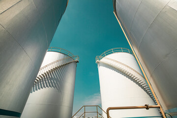 Tank farm in industry Thailand with white oil and petrol silos under blue