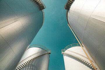 Tank farm in industry Thailand with white oil and petrol silos under blue