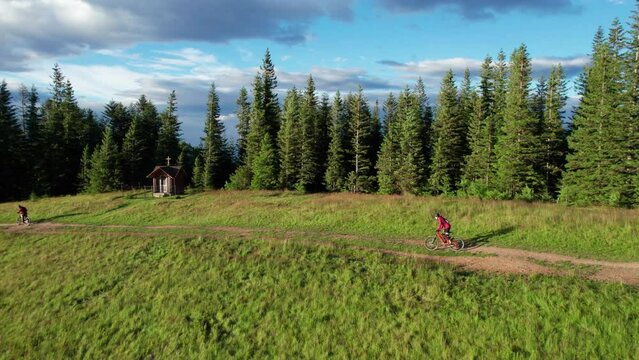 Cyclist man riding electric mountain bike outdoors. Aerial view of male tourist biking along grassy trail in the mountains, wearing helmet and backpack. Concept of sport, active leisure and nature.