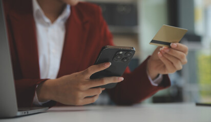 Hand holding credit card and using laptop. Businesswoman or entrepreneur working from home. Online shopping, e-commerce, internet banking, spending money, work from home concept
