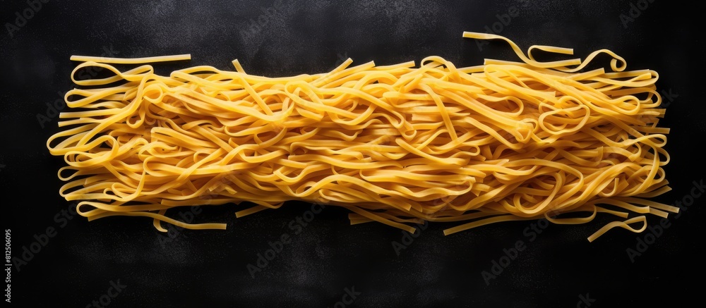 Aufkleber A set of long yellow uncooked dried pasta is arranged on a black stone background viewed from the top with ample space for text
