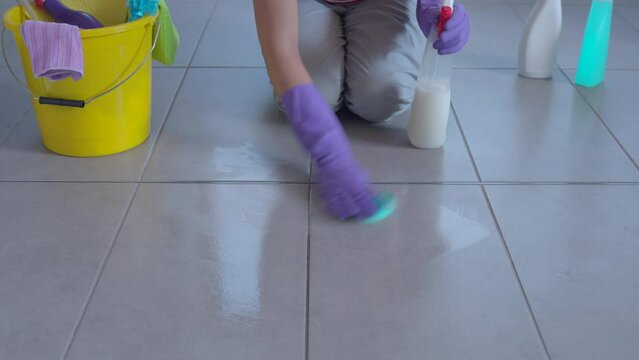 Housewife doing housework, she is cleaning the floor with a spray detergent and a sponge