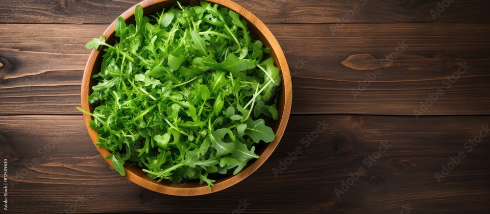 Poster a top down view of a wooden background featuring a bowl of fresh rucola salad with available copy sp