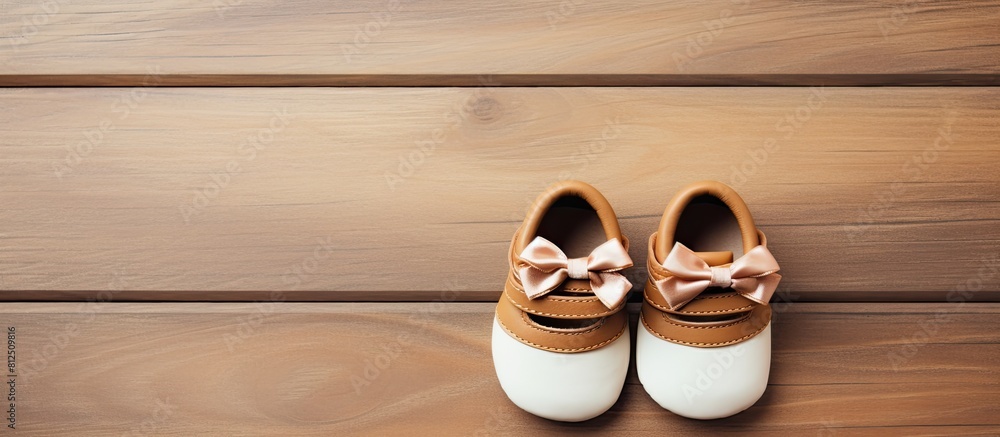 Poster Top view of adorable baby shoes placed on a wooden background creating a charming composition with copy space for an image