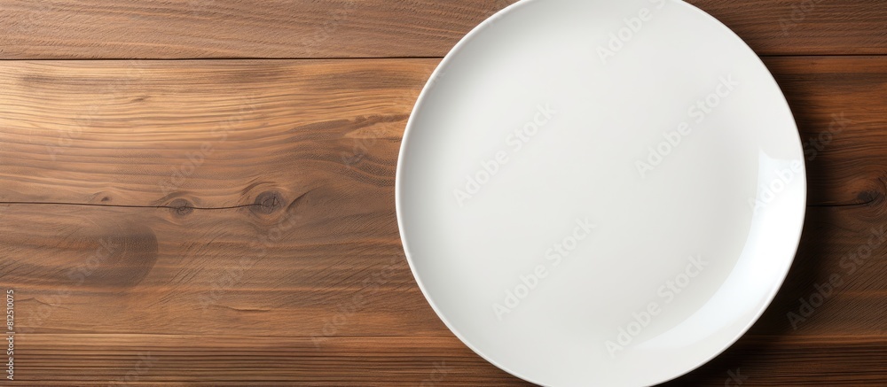 Poster Top view of a white ceramic plate placed on a wooden background and there is ample copy space in the image
