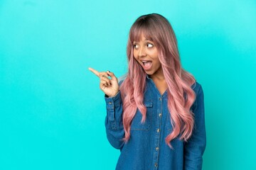 Young mixed race woman with pink hair isolated on blue background intending to realizes the...