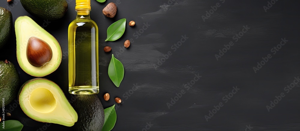 Poster top view copy space image of bottles containing avocado oil alongside slices of avocado on a grey ba
