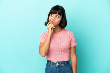 Young mixed race woman isolated on blue background and looking up