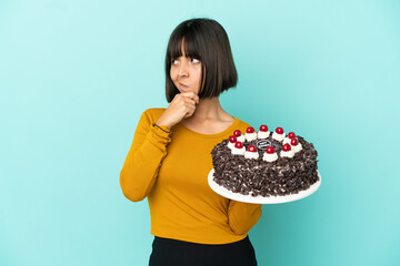 Young mixed race woman holding birthday cake having doubts and with confuse face expression