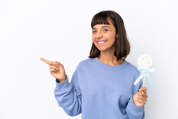 Young mixed race woman holding a lollipop isolated on white background pointing finger to the side