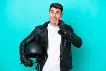 Young caucasian man with a motorcycle helmet isolated on blue background thinking an idea while looking up