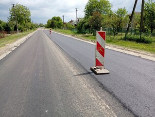 Repair of the asphalt section of the road in the village. Road signs are posted on the road section where the asphalt coating is being replaced. The topic of road and path repair.