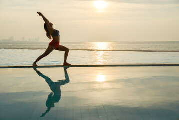 Yoga woman on the ocean during amazing sunset. Fitness and healthy lifestyle.