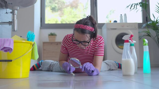 Woman cleaning the bathroom floor with a toothbrush, she is obsessed with hygiene