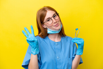 Young redhead Dentist woman isolated on yellow background happy and counting three with fingers