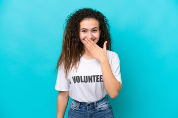 Young Arab volunteer woman isolated on blue background happy and smiling covering mouth with hand