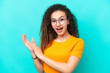 Young Arab woman isolated on blue background With glasses and applauding