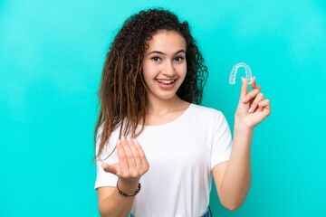 Young Arab woman holding invisible braces isolated on blue background inviting to come with hand....