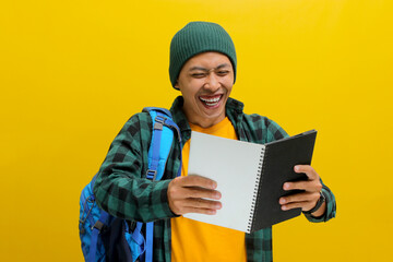 An excited young Asian student, dressed in a beanie hat and casual shirt, carrying a backpack,...