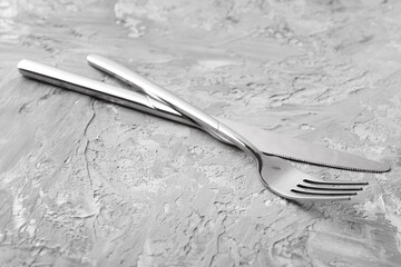 Stylish cutlery. Silver knife and fork on grey textured table