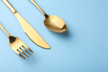 Stylish cutlery set on light blue table, above view. Space for text
