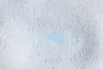 White fluffy foam on light blue background, top view