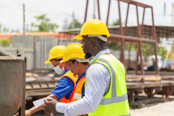 Foreman and worker team checking project at the precast factory site, Engineer man and builders in hardhats discussing on construction site