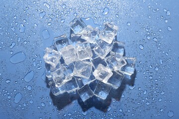 Pile of melting ice cubes and water drops on blue background, top view