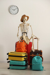Waiting concept. Human skeleton in hat with suitcases indoors