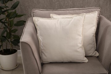 Soft pillows on grey armchair in room