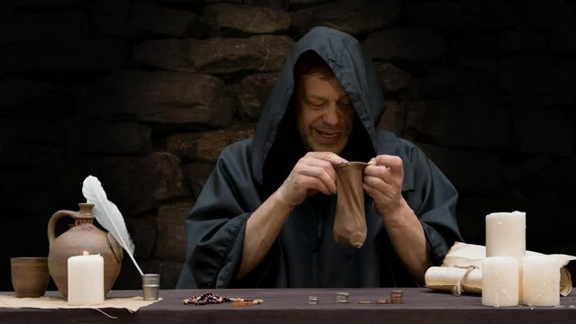 A greedy monk treasurer counts and pours money into a leather purse, sitting at a table against a stone wall, candles burning.