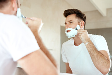 Man, mirror and shaving face with razor in bathroom for grooming, skincare or morning routine....