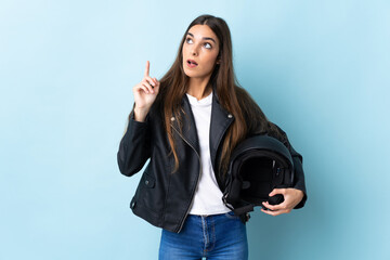 Young caucasian woman holding a motorcycle helmet isolated on blue background thinking an idea...