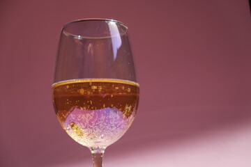 Wine in a holographic glass on a pink background. Lemonade in a glass. Champagne in a glass. Party. Alcohol. Glass of wine.