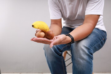 Asian man holding a banana and eggs, Size matters concept and penis size measurement.