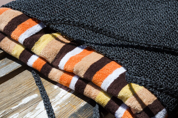 Black eco-friendly raffia bag and colorful towel on old wooden background.