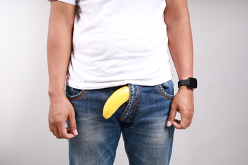 Limp drooping banana hanging from genital area of clothed unrecognizable man, impotence erectile...