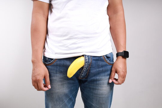 Limp drooping banana hanging from genital area of clothed unrecognizable man, impotence erectile dysfunction or limp-dick concept