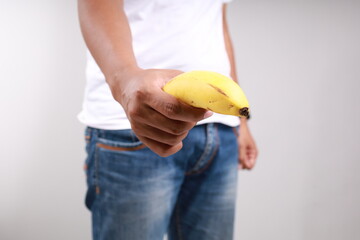 Asian man holding a banana, Size matters concept and penis size measurement.
