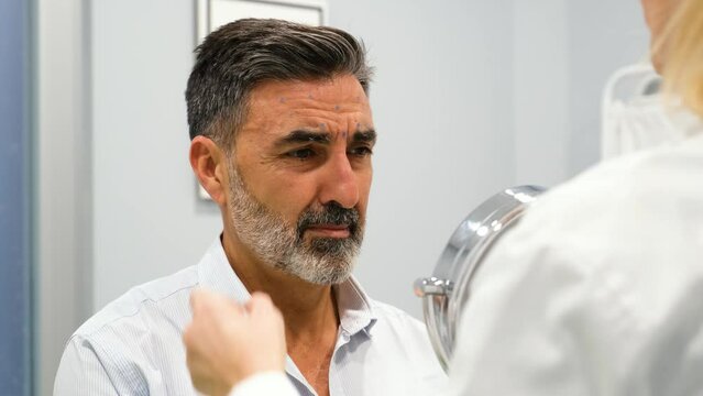 A man is getting ready to get Botox for forehead wrinkles, crow's feet or laugh lines wrinkles by a aesthetic doctor in a clinic.