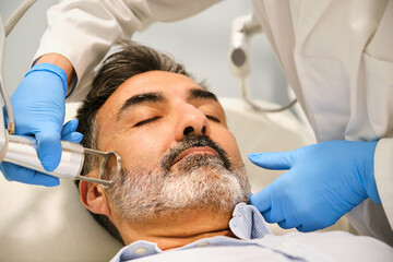 A man is getting a laser skin resurfacing treatment by a aesthetic doctor in a clinic.