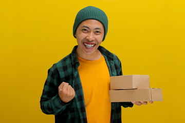 Happy Asian customer joyfully raises his arm in a YES gesture while holding package parcel...