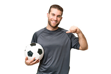 Young handsome blonde man over isolated chroma key background with soccer ball and proud of himself