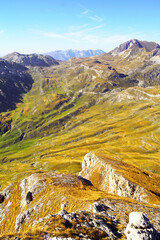 Aerial view of the Dobri do valley in Durmitor National Park, Montenegro. Bright autumn landscape from the highlands: a valley covered with green and yellow grass and mountain peaks in the background