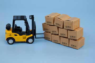 Many carton boxes and yellow forklift truck. Logistics, delivery and transportation concept.