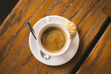 A From above of a freshly brewed cup of black coffee. Coffee cup top view on wooden table background.