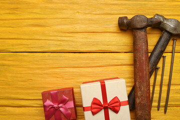 Labor day or father day concept background. Present gift box and work tool hammer and nails on the...